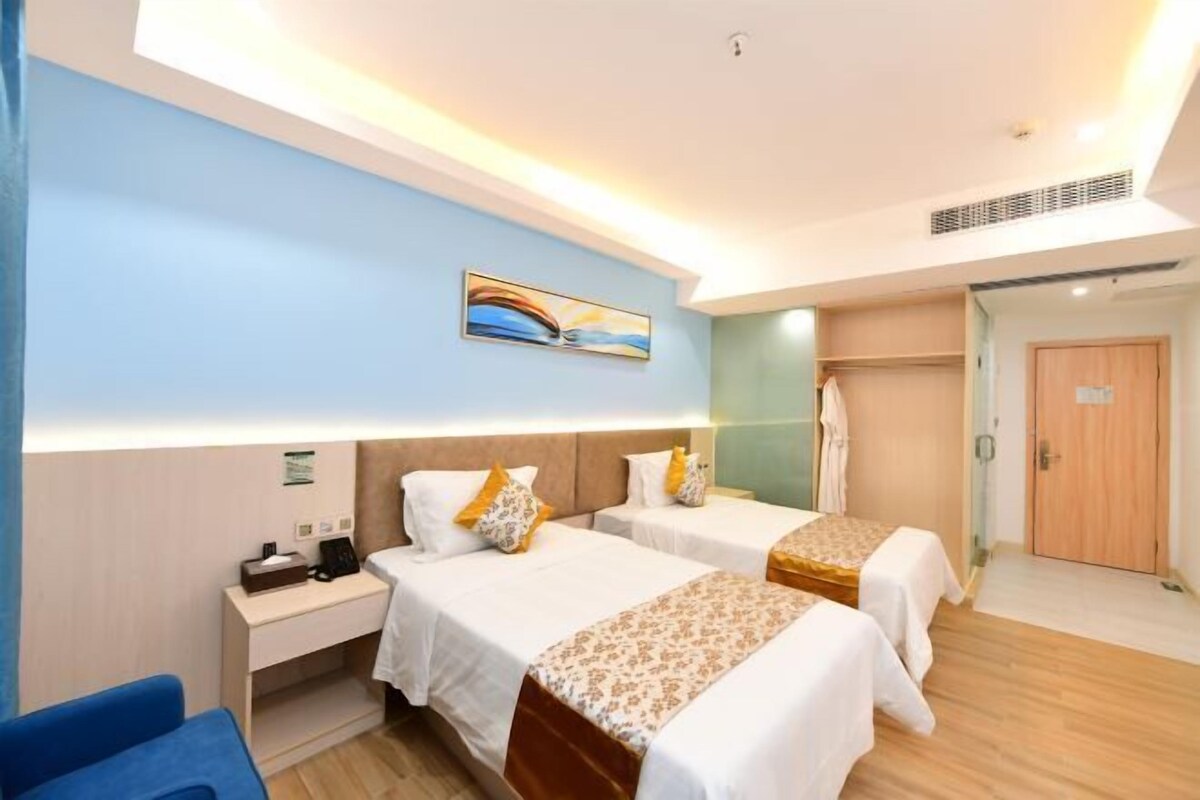 Une chambre d’hôtel avec deux lits, un bureau, une chaise et un tableau au mur.