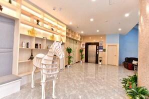 A hotel lobby with a reception desk, a white horse sculpture, and a reception area with a blue wall. - Shanshui Trends Hotel (Sha Village MTR station store Guangzhou) (Guangzhou)
