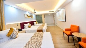 Una habitación de hotel con tres camas, un escritorio y dos sillas.