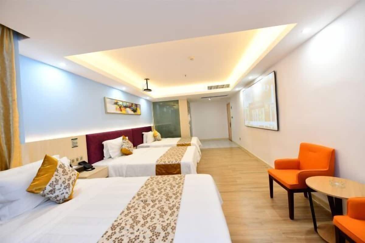 A hotel room with two beds, a desk, a chair, and a small table.