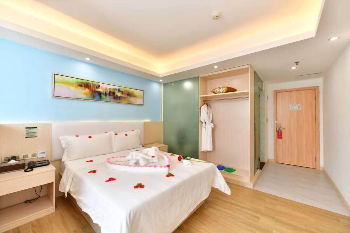 A hotel room with a bed, bedside table, and a robe closet.