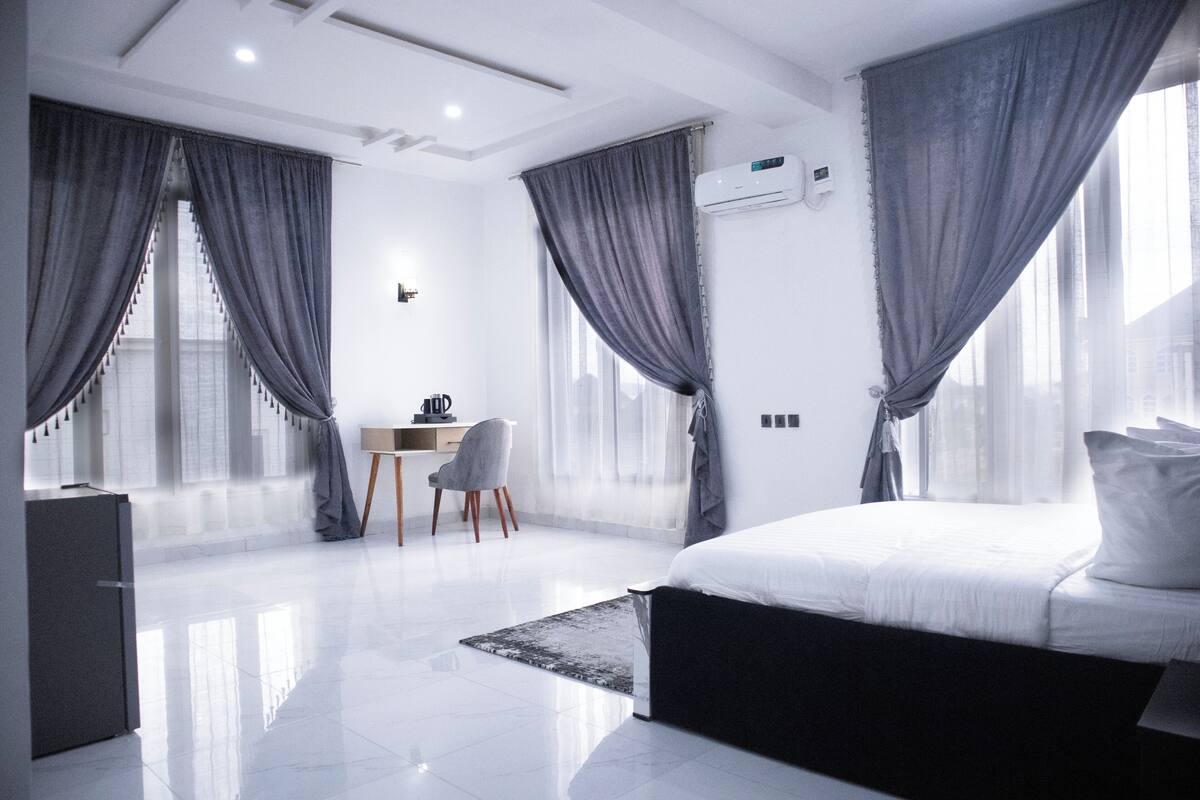 A modern hotel room with a large bed, a desk, and a chair.