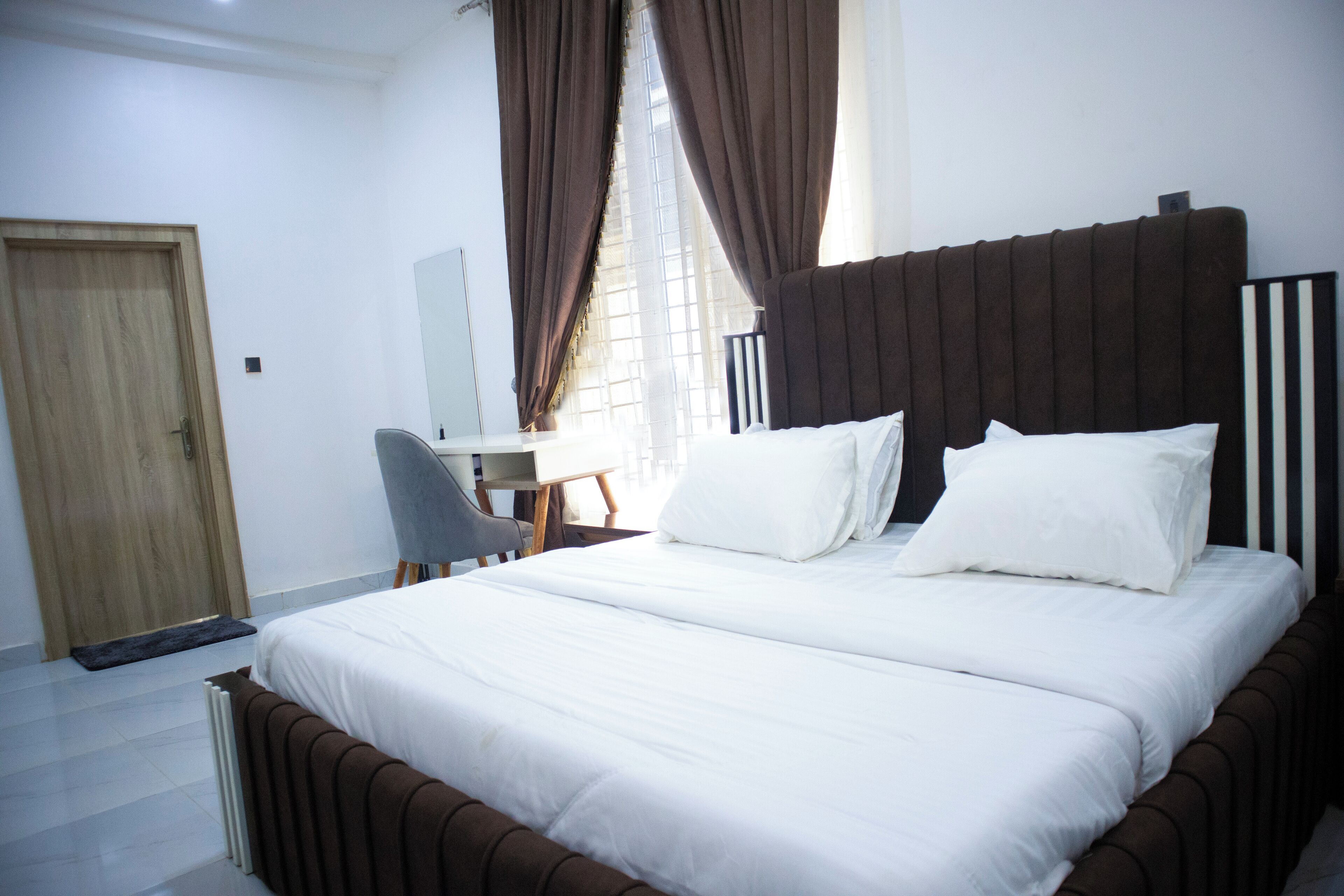 A bedroom with a large bed, a desk, and a chair.