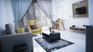 A modern living room with a sofa, armchair, coffee table, and a TV mounted on the wall. - Kyeston Apartment (Abuja)