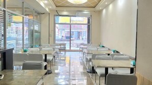 Un salón de conferencias con mesas y sillas, ventanas amplias y un candelabro.