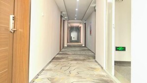 Un pasillo de hotel con alfombra estampada, puertas de madera y un cartel que indica una salida.