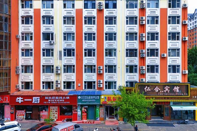 Un edificio de varios pisos con una fila de tiendas en la planta baja, unidades de aire acondicionado en el exterior y un letrero con caracteres chinos.