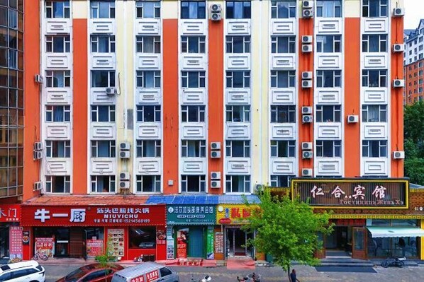 Un edificio de varios pisos con una fila de tiendas en la planta baja, unidades de aire acondicionado en el exterior y un letrero con caracteres chinos.