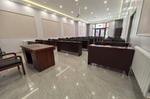 Un salón de conferencias con una larga mesa, filas de sillas y un atril.