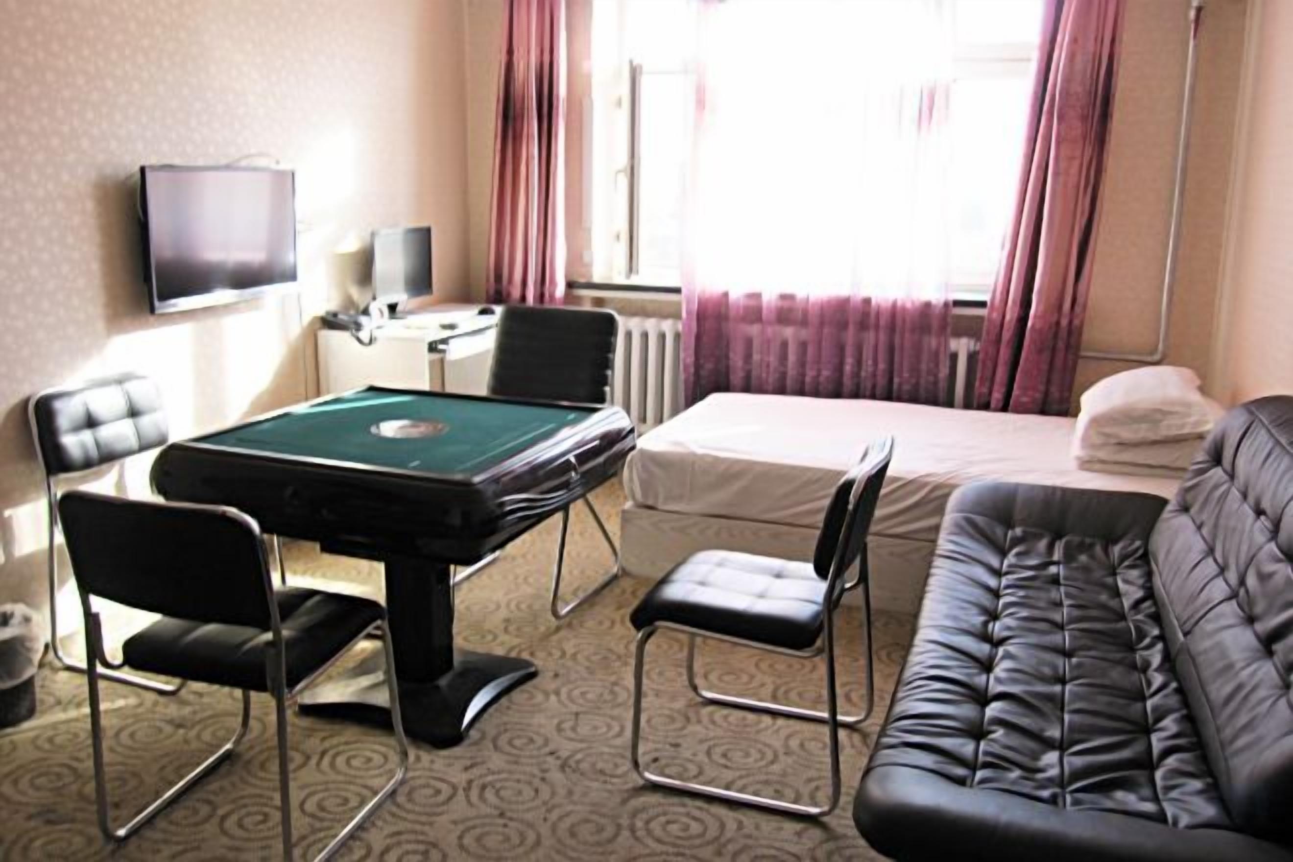 A hotel room with a pool table, a bed, a sofa, and a television.