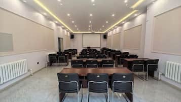 A conference room with a long table and chairs, a projector screen, and a whiteboard.
