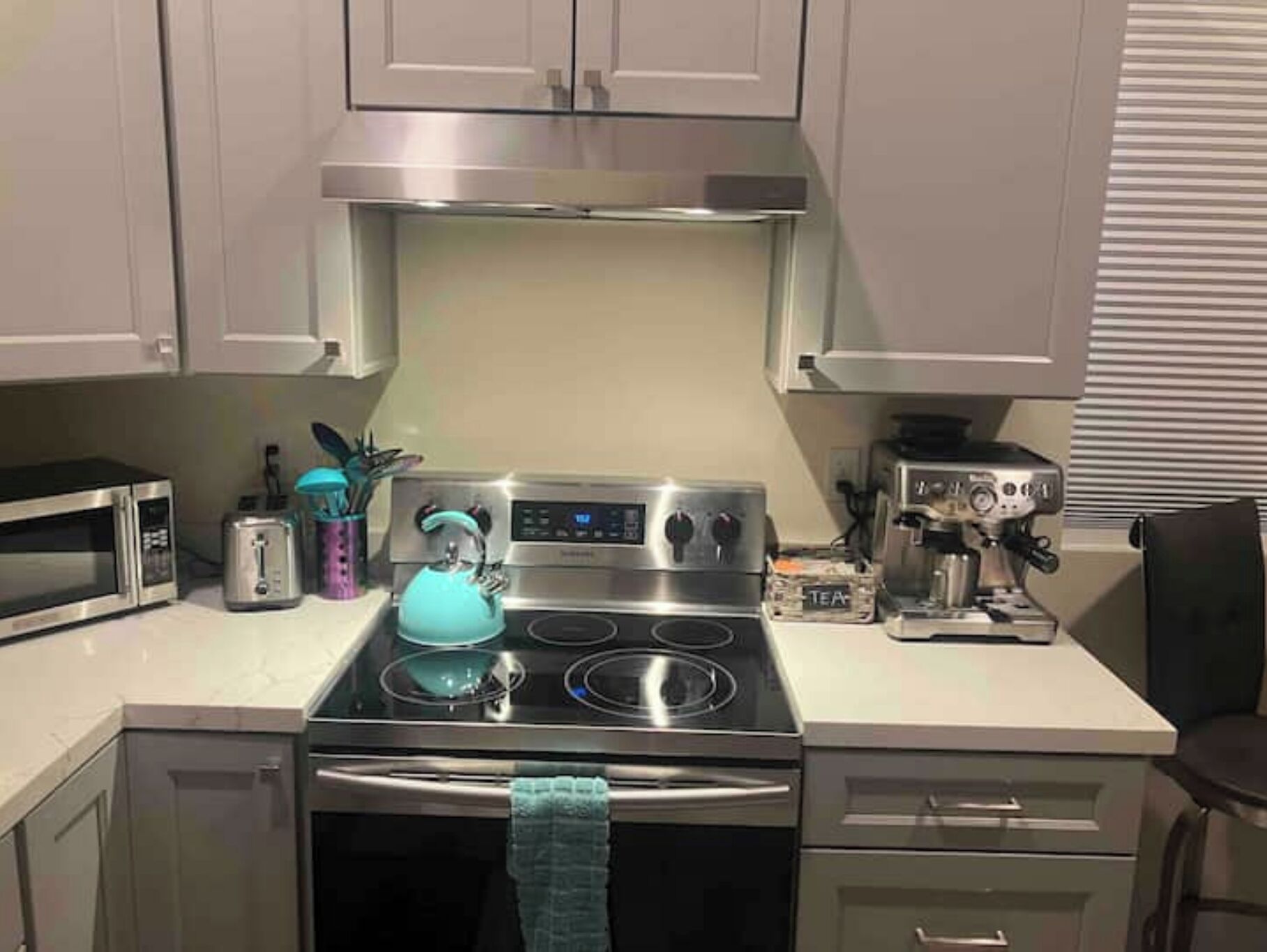 Una cocina con estufa de acero inoxidable, microondas y tostadora.