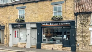 Un bâtiment en pierre de deux étages, dont le rez-de-chaussée abrite un magasin Yorkshire Kitchens & Interiors.