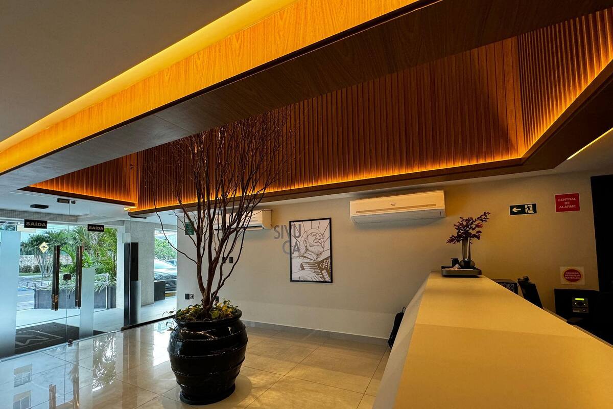 A reception area with a modern design, including a reception desk, a potted plant, and a wall-mounted artwork.
