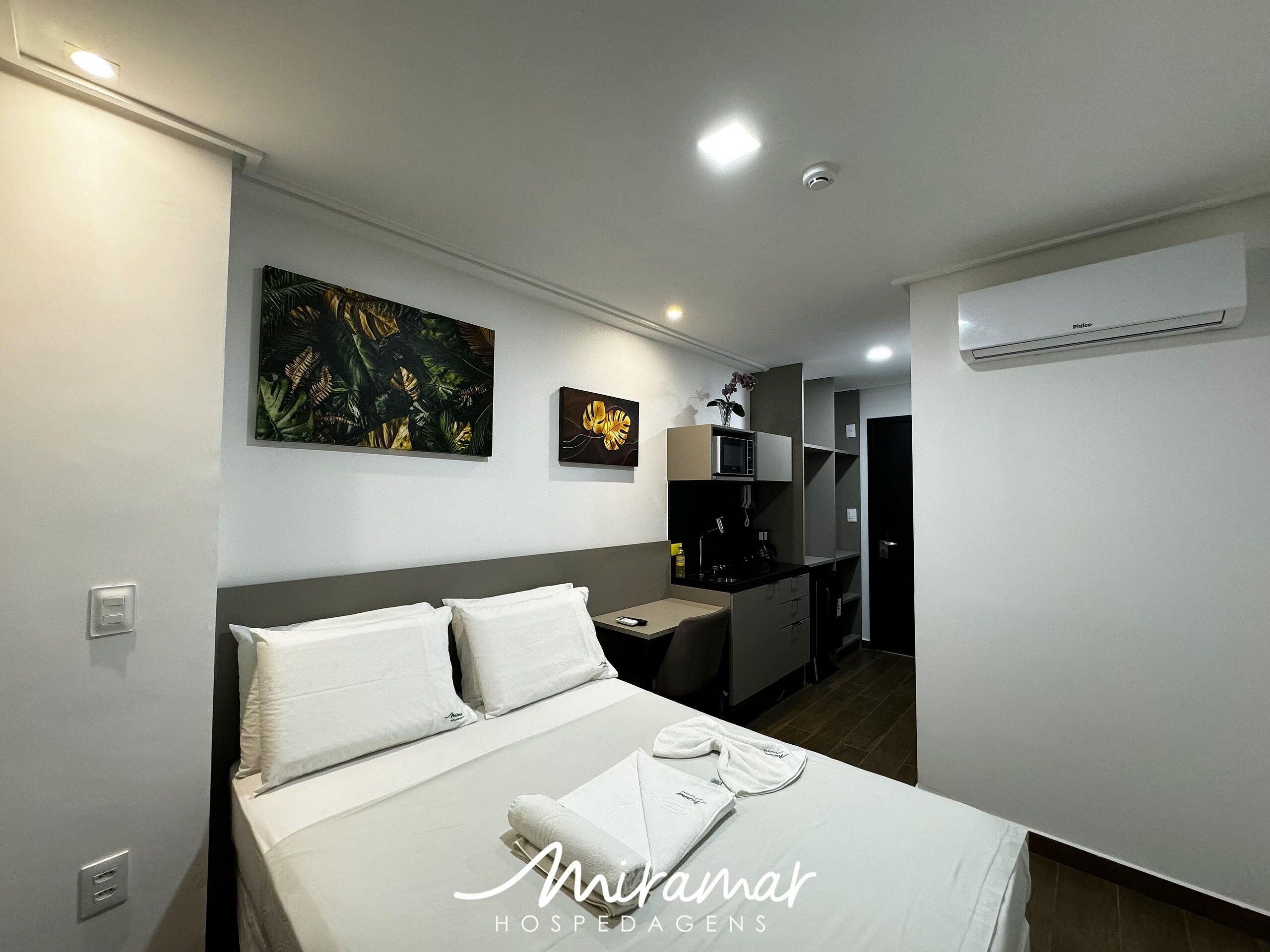 A hotel room with a bed, a desk, a microwave, and a small kitchen area.