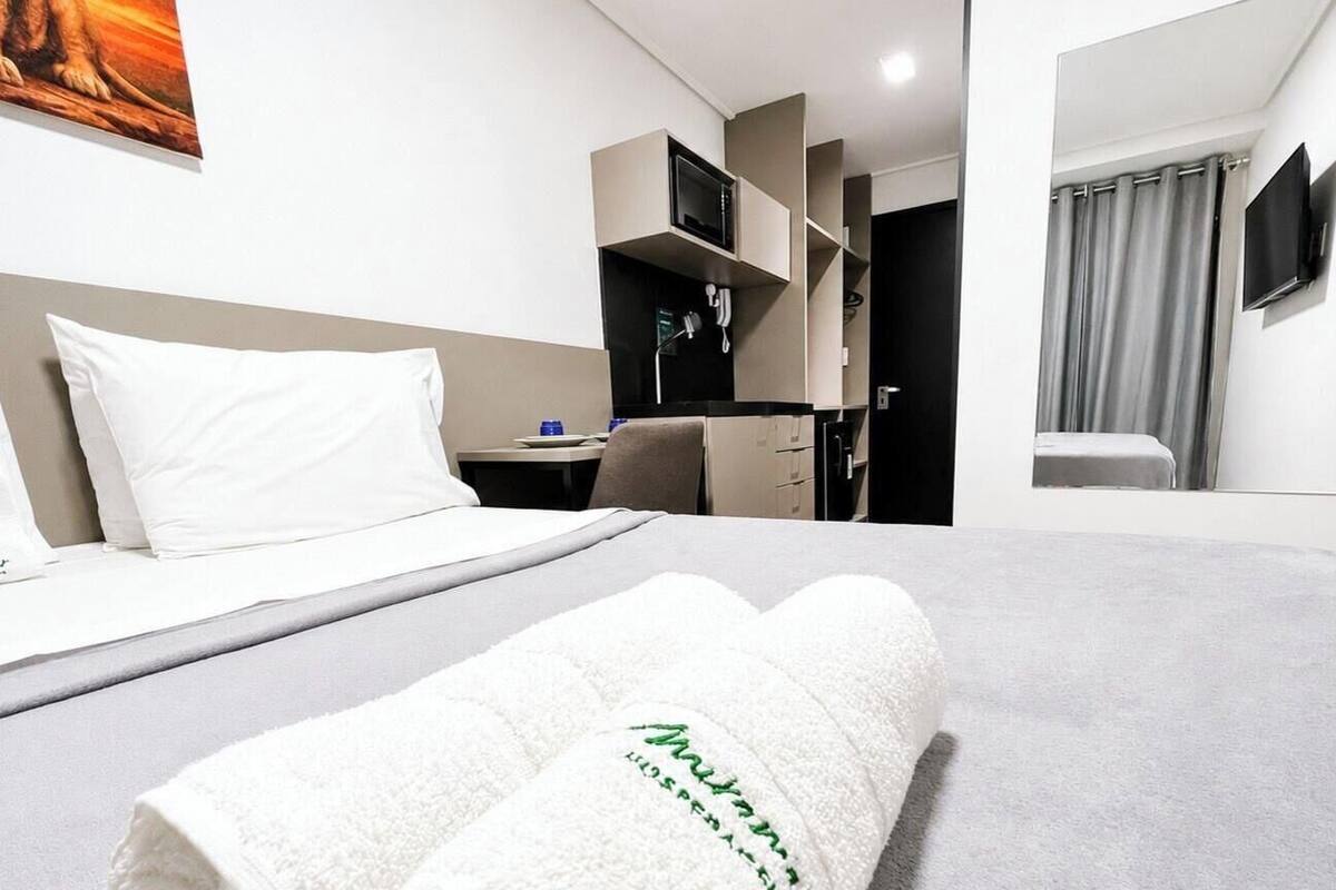 A hotel room with a bed, a desk, a chair, a television, and a bathroom.