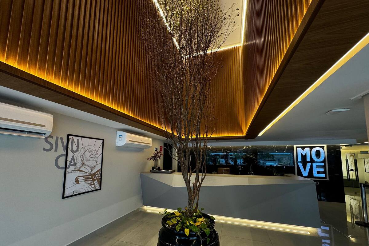 A reception area with a modern design, including a reception desk, a potted plant, and a framed artwork on the wall.