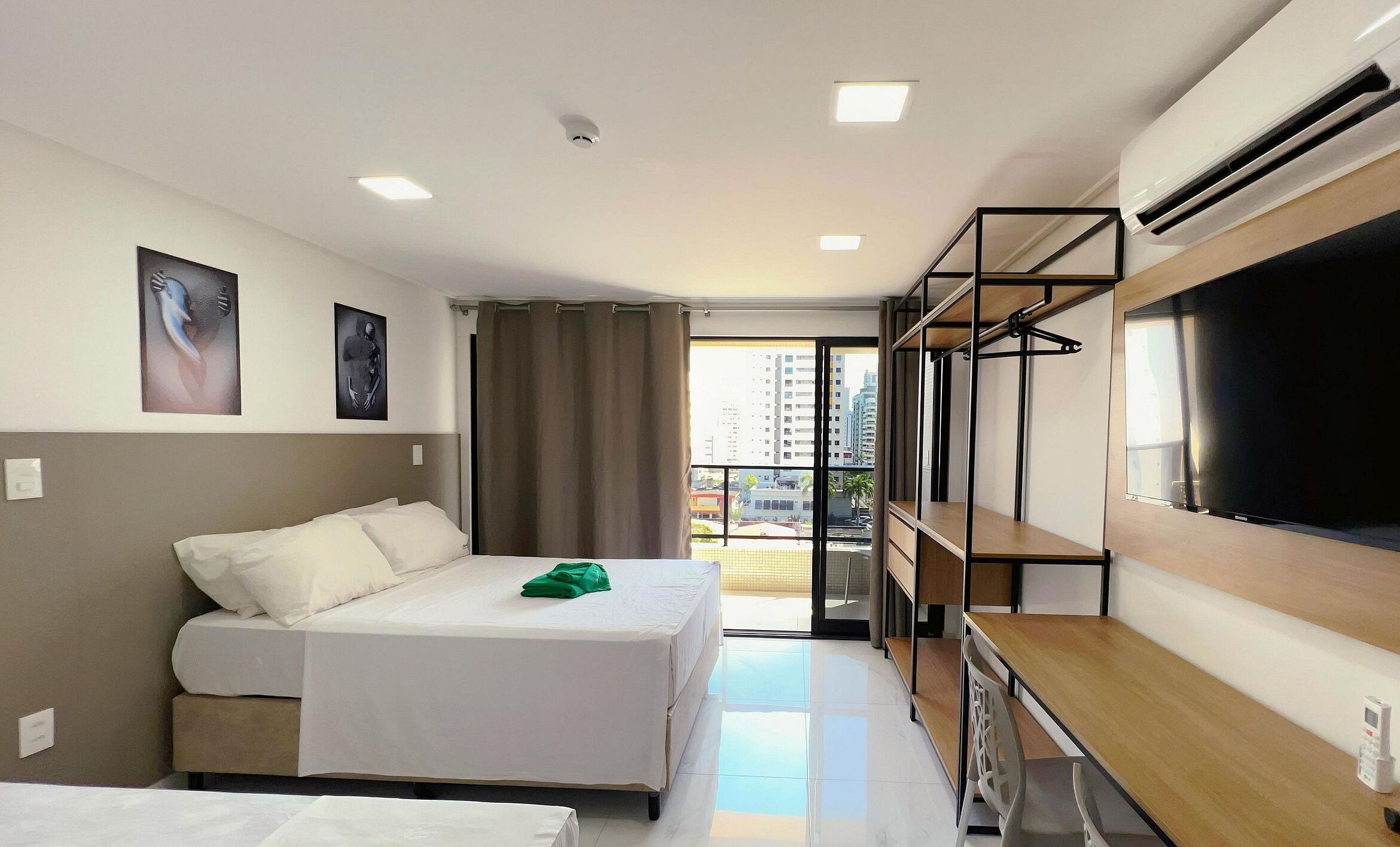 Une chambre d’hôtel avec un lit, un bureau, une télévision et une vue sur la ville.
