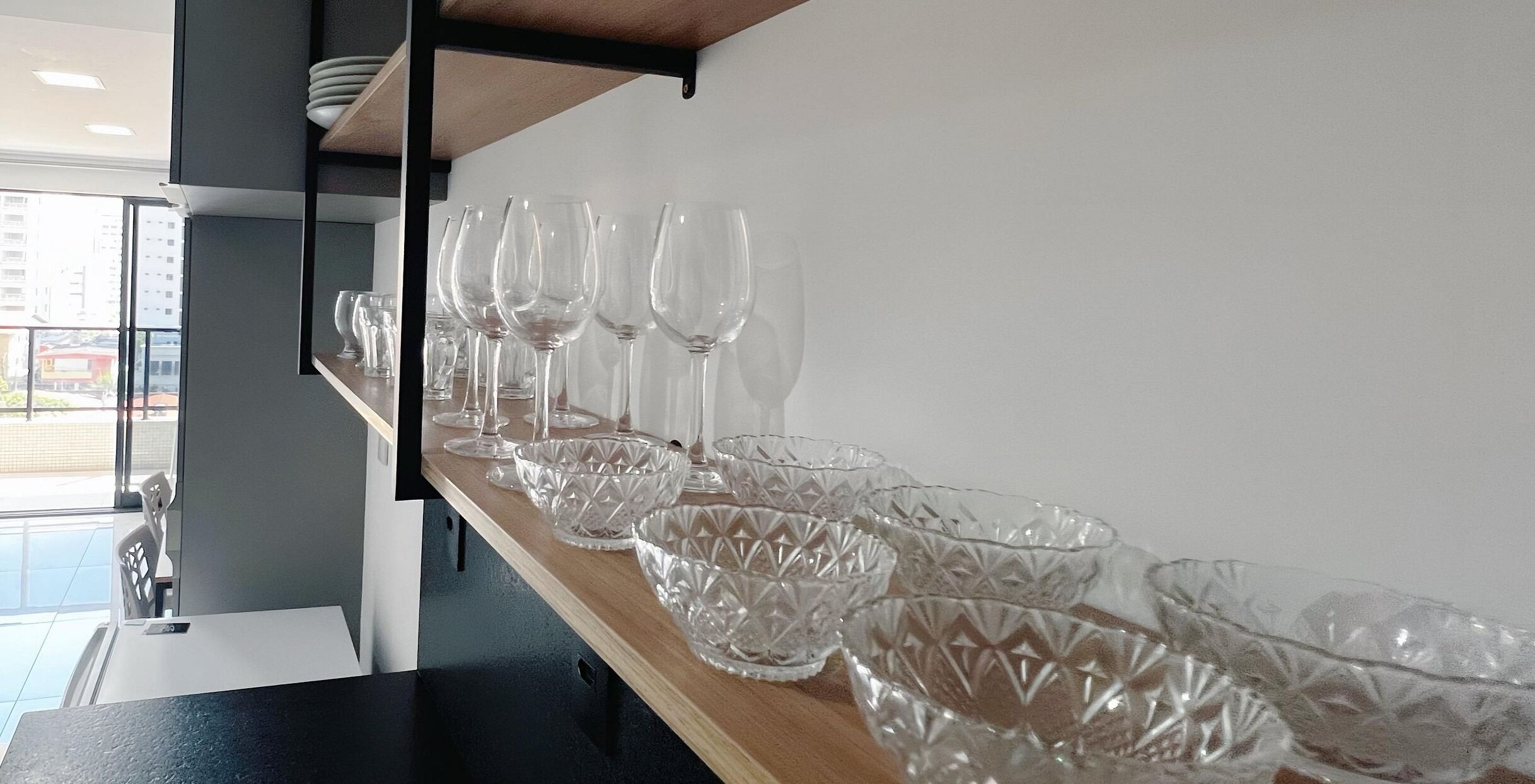 En bardisk med en rad tomma vinglas och kristallskålar uppradade på en hylla av trä.