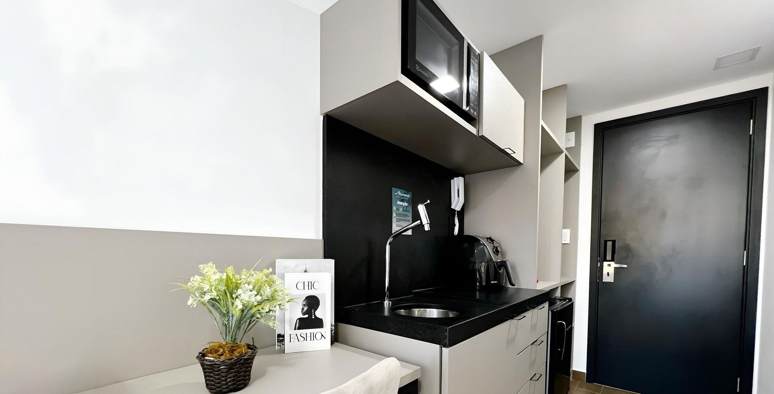 A modern kitchen with a black countertop, stainless steel sink, and a black door.