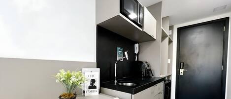A modern kitchen with a black countertop, stainless steel sink, and a black door.
