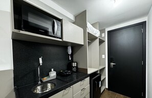 A compact kitchen with a microwave, coffee maker, and a sink. - MOVE (João Pessoa)