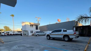 Un parking avec une place réservée aux personnes handicapées, un camionnette blanche et un bâtiment sur lequel on peut lire l’inscription « OXO ».