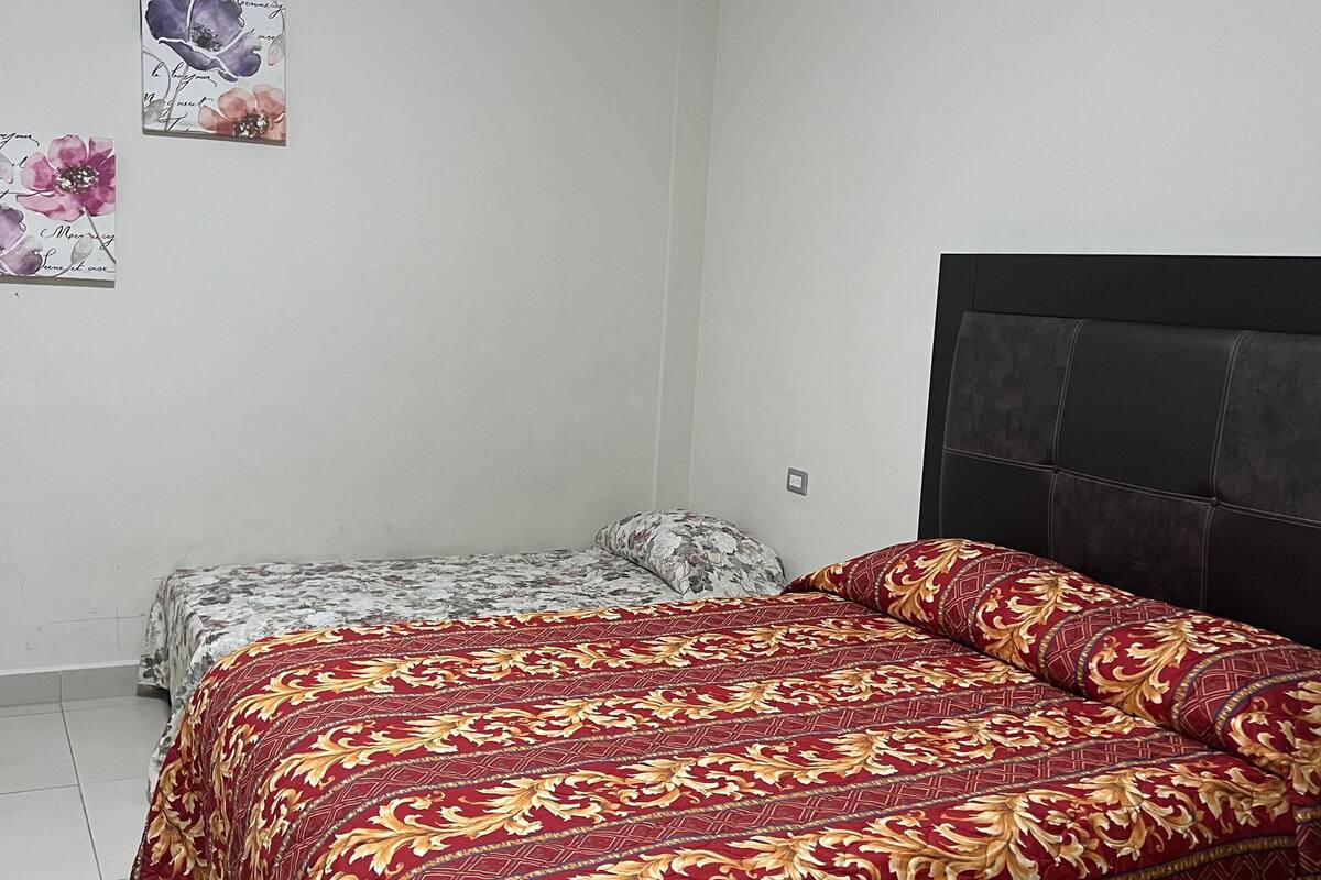 A bedroom with a large bed, a smaller bed, and a headboard.