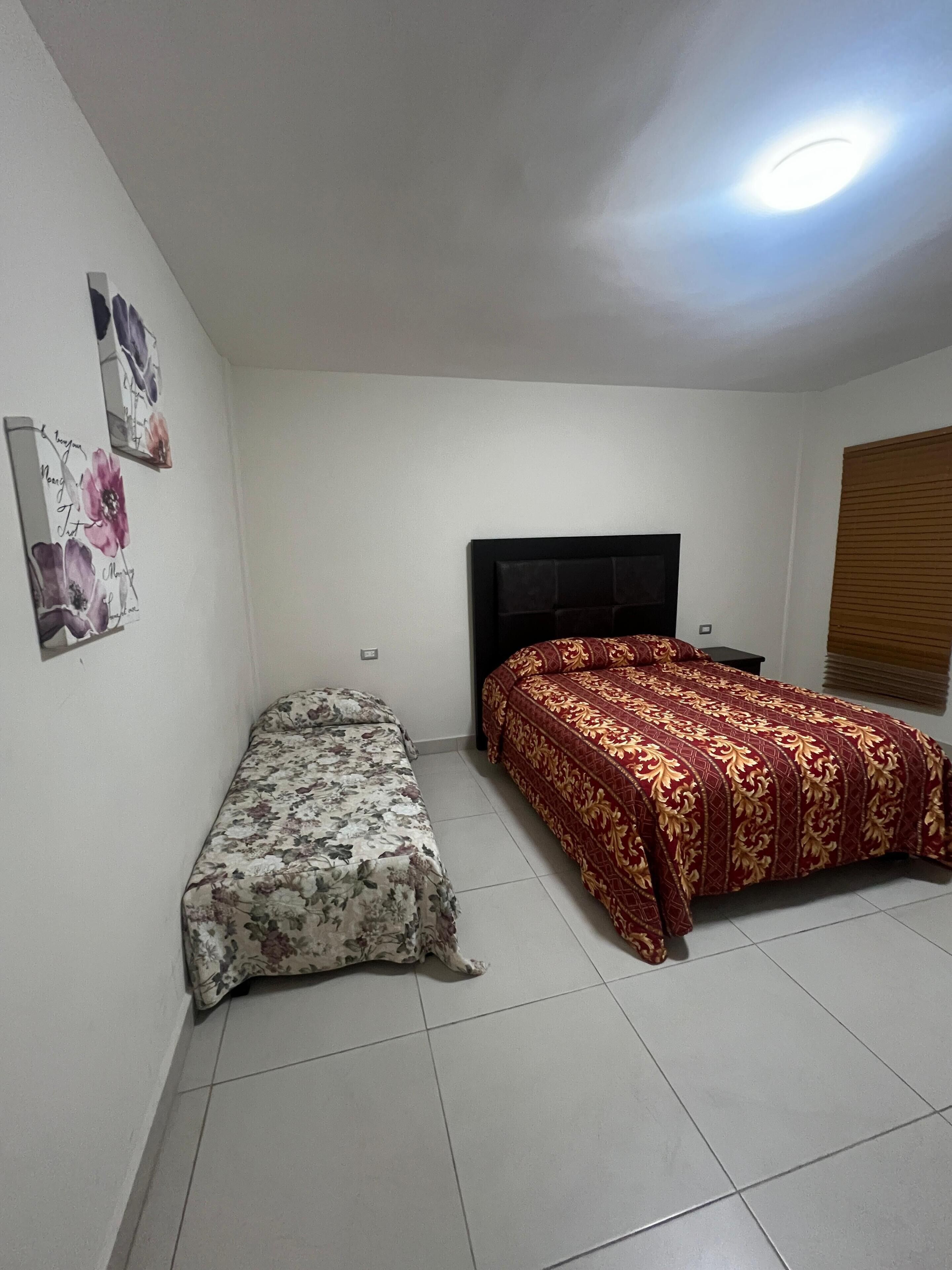 A bedroom with a bed, a bench, and a TV.