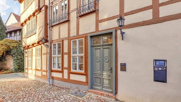 Un edificio tradicional europeo con una calle adoquinada, una puerta verde y un buzón.