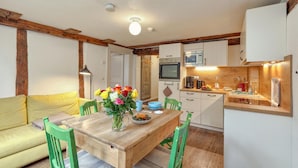 Una cocina acogedora con vigas de madera, una mesa de comedor con sillas y un pequeño rincón de comedor.