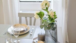 A dining table set with plates, glasses, and a vase with flowers, with a view of a body of water and mountains through a window. - Your window on Varenna-Como-. (Varenna)
