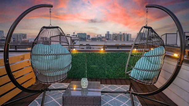 Une terrasse sur le toit, avec deux fauteuils suspendus, une table et une vue sur le panorama urbain.
