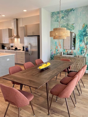 Une cuisine moderne dotée d’un îlot central, d’appareils électroménagers en acier inoxydable et d’un coin repas avec une table en bois et des chaises assorties.