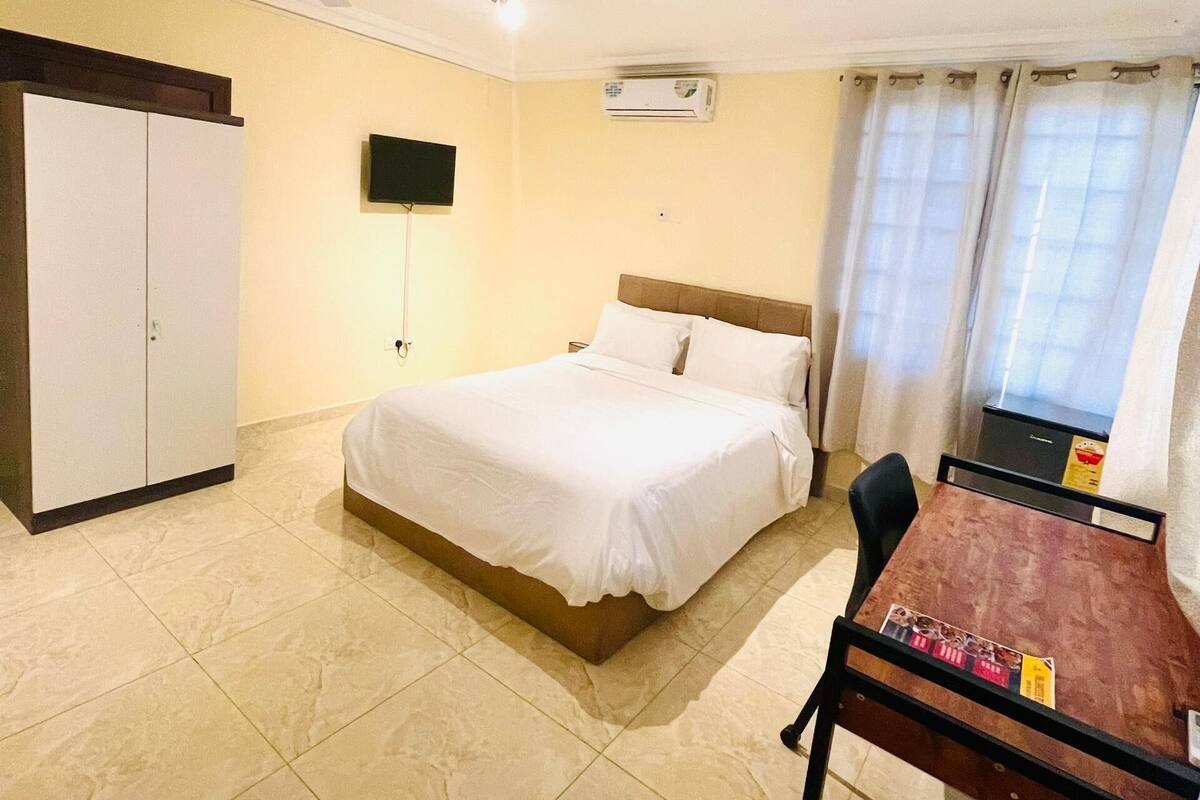 Une chambre d’hôtel équipée d’un lit, d’un bureau, d’une armoire et d’un appareil de climatisation.