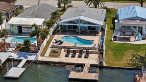 A residential property with a swimming pool, dock, and a covered patio area. - Remodeled Waterfront Home with Heated Pool (New Port Richey)