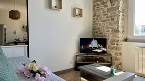 Ett modernt vardagsrum med en vägg av sten, en platt-TV, ett soffbord i trä och en blomsteruppsättning på soffan.