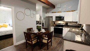 Una cocina compacta con armarios blancos, un microondas y un refrigerador de acero inoxidable.