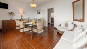 Uma sala de estar moderna com área de jantar, apresentando piso de madeira, móveis de vime e um espelho grande.