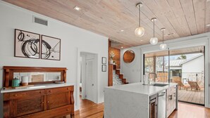 A modern kitchen with a marble island, wooden cabinetry, and pendant lighting. - Private East Austin Estate - Heated Pool - 4BR/4BA (Austin)
