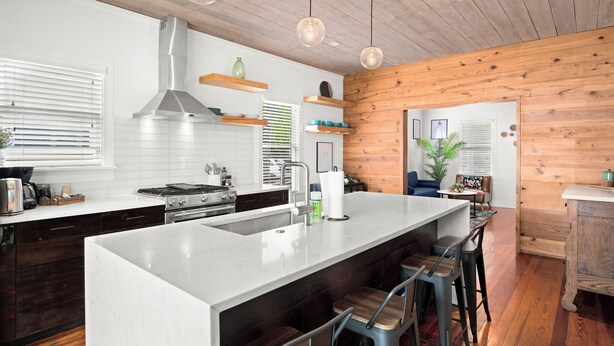 A modern kitchen with a large island, wooden ceiling, pendant lights, and a view into the living area. - Private East Austin Estate - Heated Pool - 4BR/4BA (Austin)