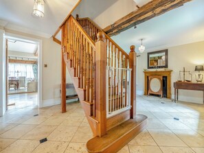 A wooden staircase with a railing, a fireplace with a mirror above it, and a dining area visible through an open door.