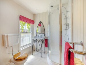 Een badkamer met toilet, wastafel, douche en een raam met uitzicht.