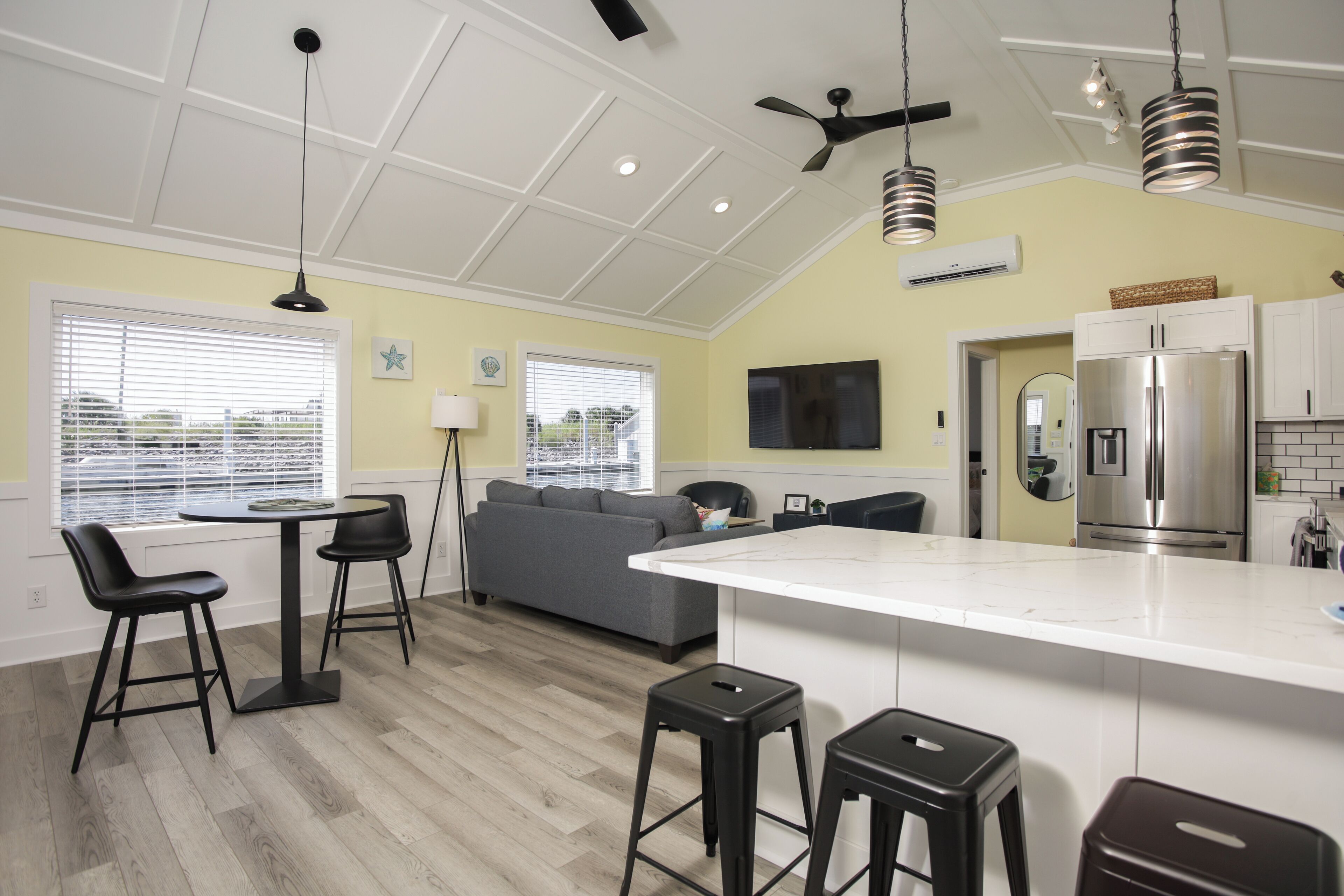 A modern kitchen with a central island, bar stools, and a built-in refrigerator.