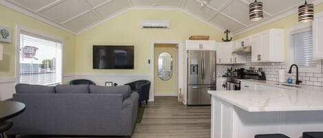 A modern kitchen with white cabinets, a stainless steel refrigerator, and a marble island.
