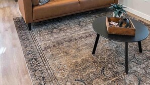 A cozy living room with a brown leather sofa, a black coffee table, and a patterned rug. - Paddlewhack Cabin 2 - FlyBridge (Jefferson)