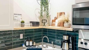 A modern kitchen with a wooden ceiling, a hanging plant, a coffee maker, and a microwave. - Paddlewhack Cabin 5-The Bow (Jefferson)