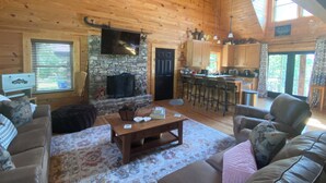A cozy log cabin interior with a stone fireplace, wooden furniture, and a kitchen area. - Chase N' Sunsets - NEW Listing, Brow view, between Mentone & Little River Canyon (Fort Payne)