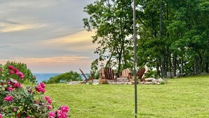 A grassy outdoor area with a view of the sea, wooden chairs, and a stone wall. - Chase N' Sunsets - NEW Listing, Brow view, between Mentone & Little River Canyon (Fort Payne)