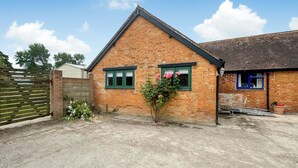 A brick building with two windows, a small garden with flowers, and a concrete driveway. - 3 bedroom accommodation in East Orchard, near Shaftesbury (East Orchard, near Shaftesbury)